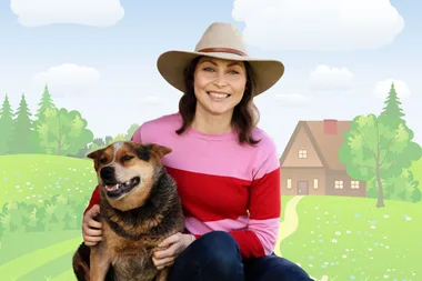 A woman smiling with a dog. She is wearing a hat and a pink and red shirt. The background is a cartoon style picture of the countryside.