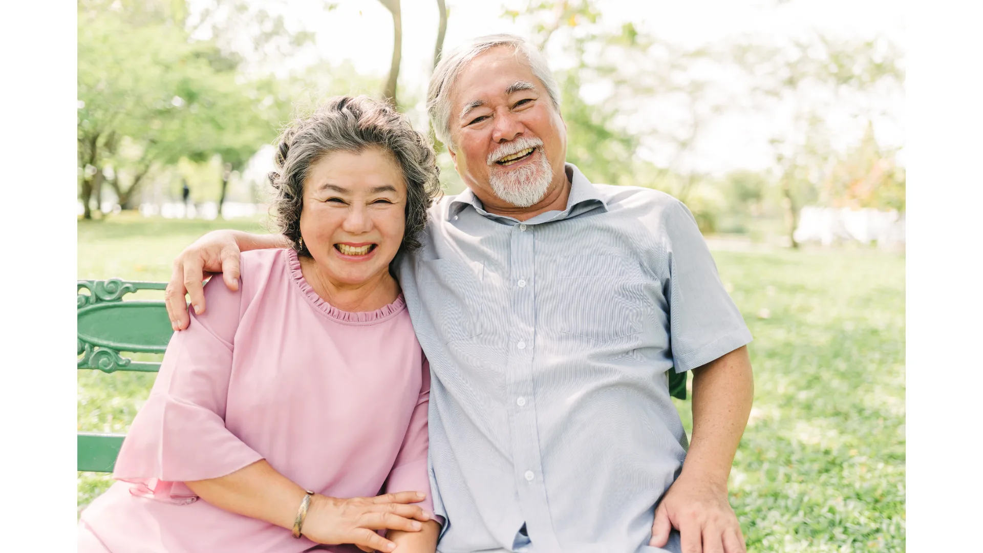 An older Japanese couple share a laugh as they embrace.