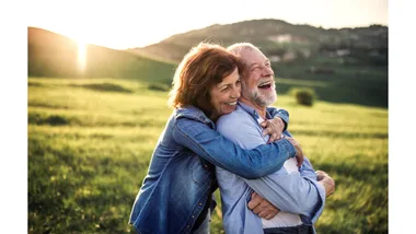 An older couple share an embrace while out in nature.