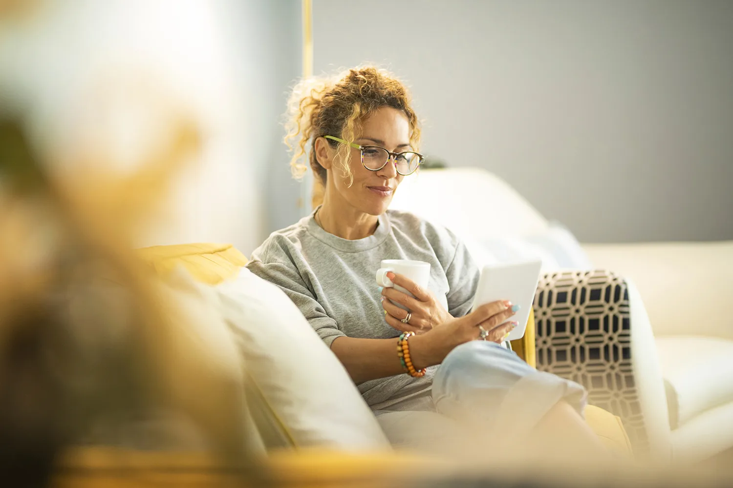 Middle age woman at home on the couch reading an electronic reading device