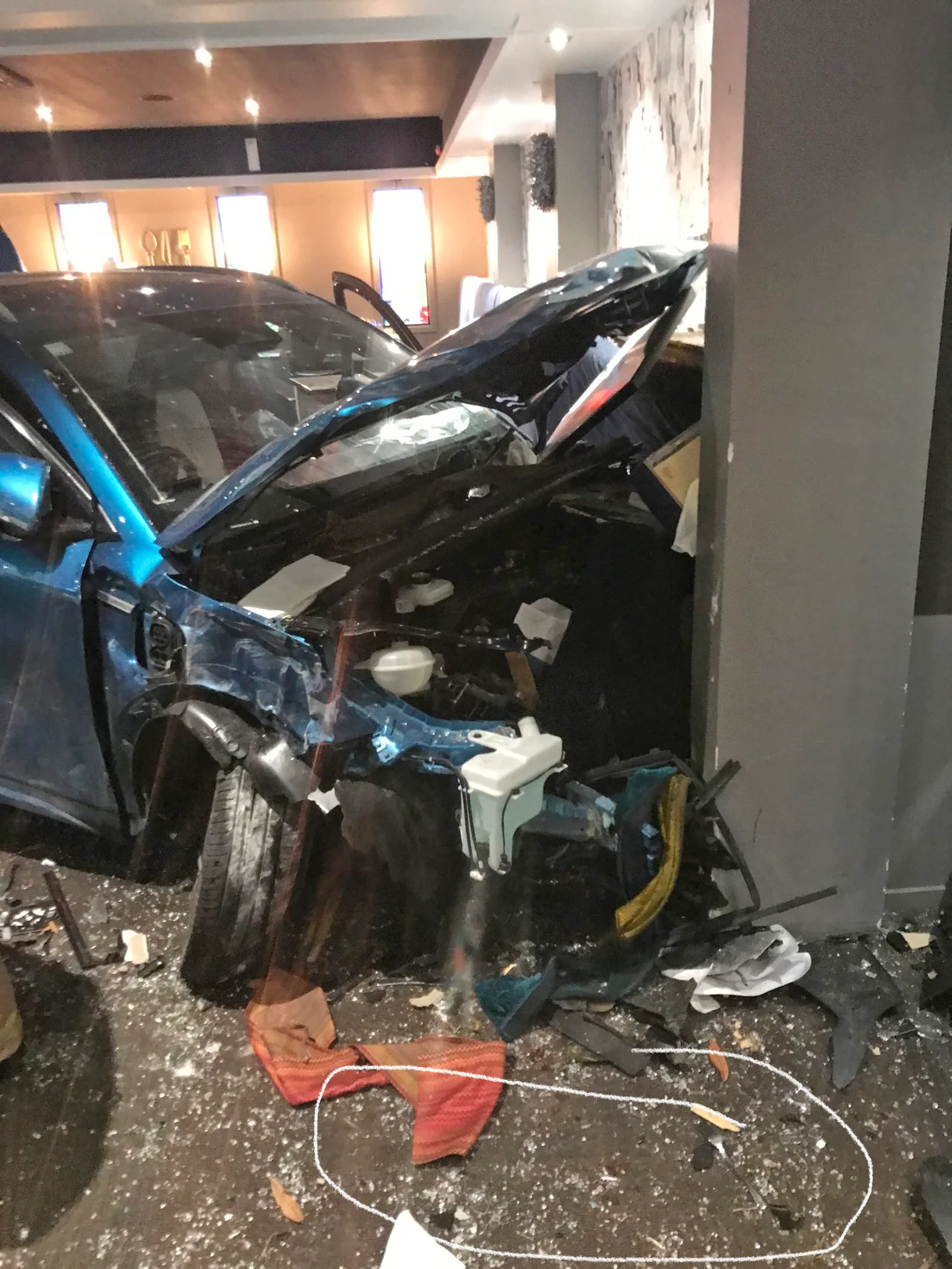 A blue car crumpled into a concreate pillar
