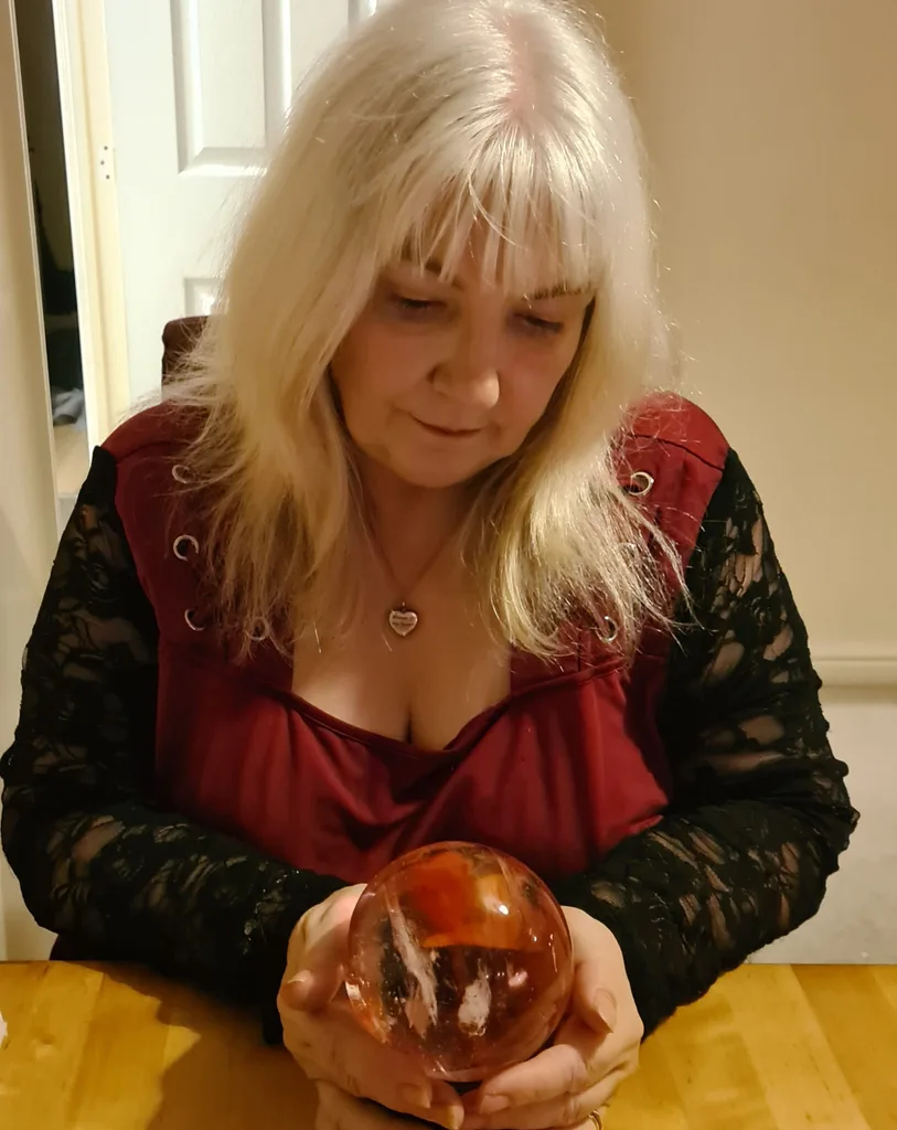 WOMAN in red dress looking at crystal ball