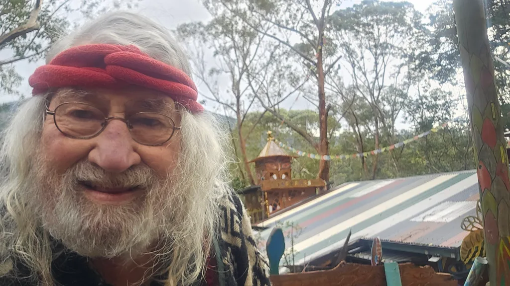 A picture of Bob now smiling at the camera. In the background is his treehouse.