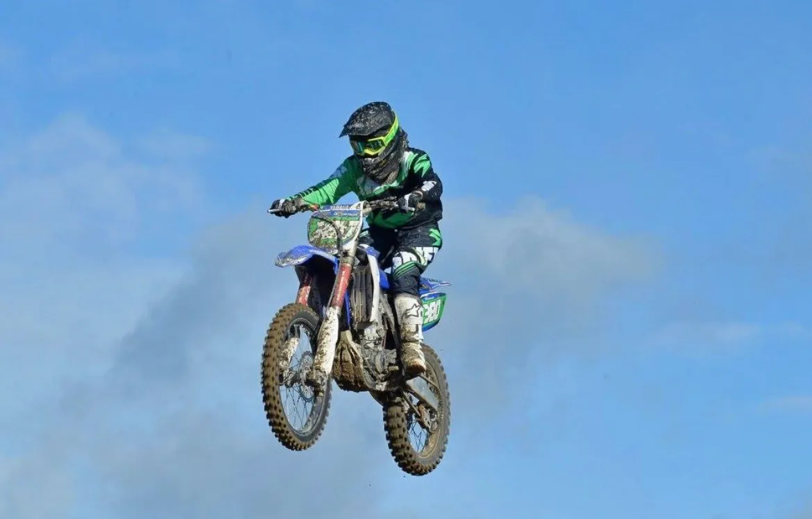 woman riding motorcross bike she is mid-air and the bike is blue and green