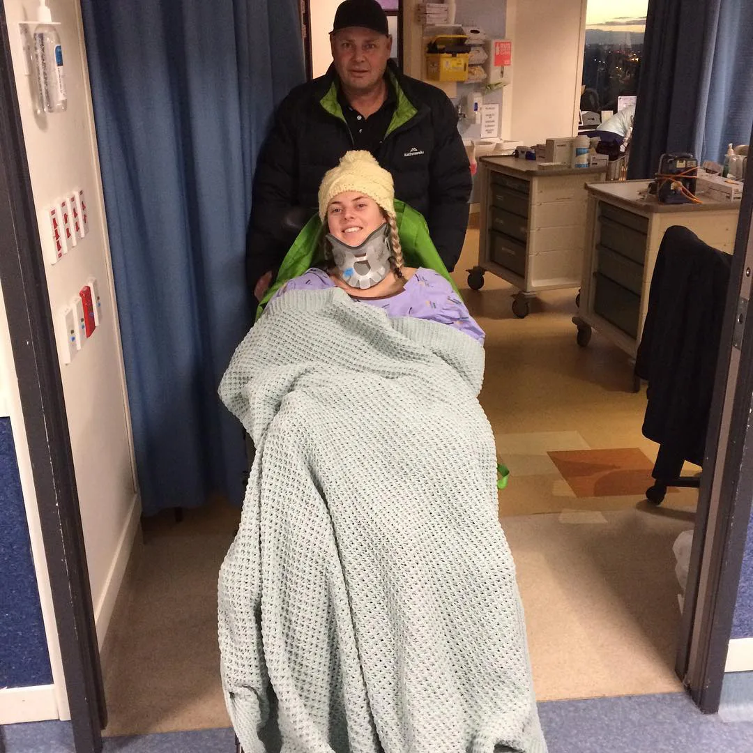 woman in wheelchair covered in grey blanket, a man pushes her