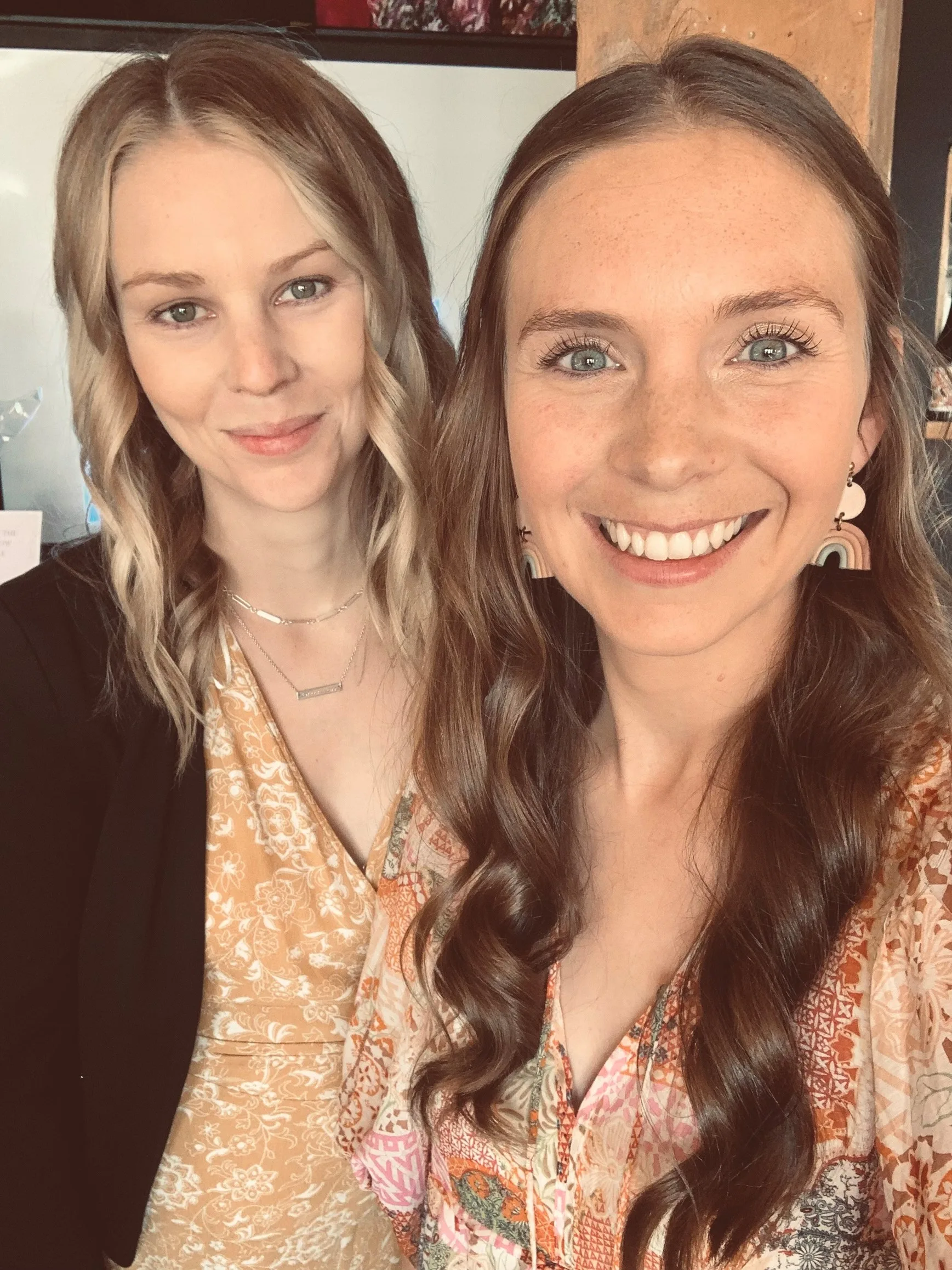two smiling women in floral dresses