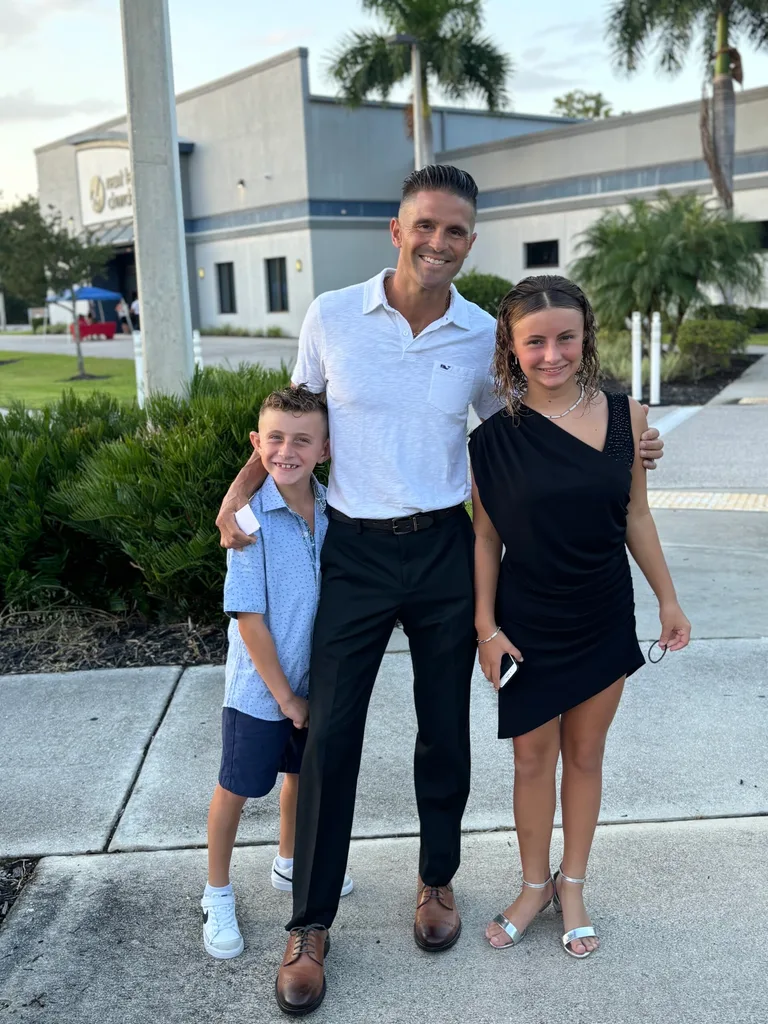 a man with his two children smiling outside