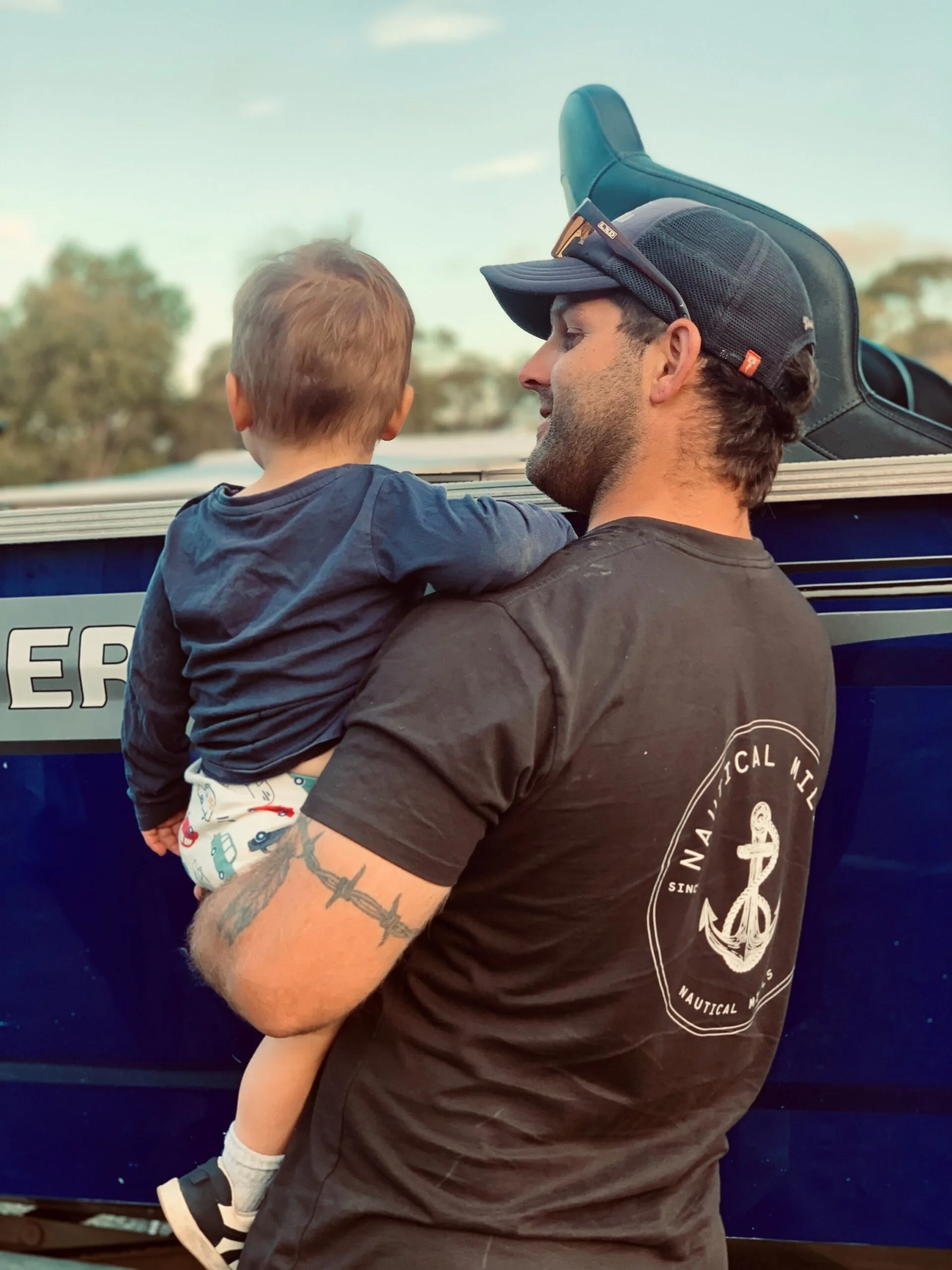 man in brown tshirt holding boy in blue tshirt