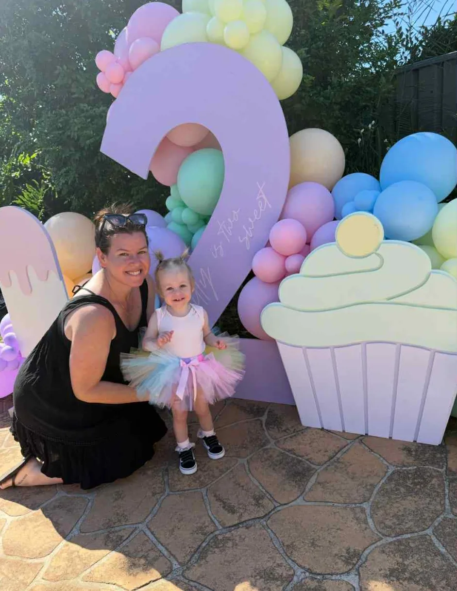 Image of mum and daughter celebrating second birthday, little girl is wearing rainbow tutu