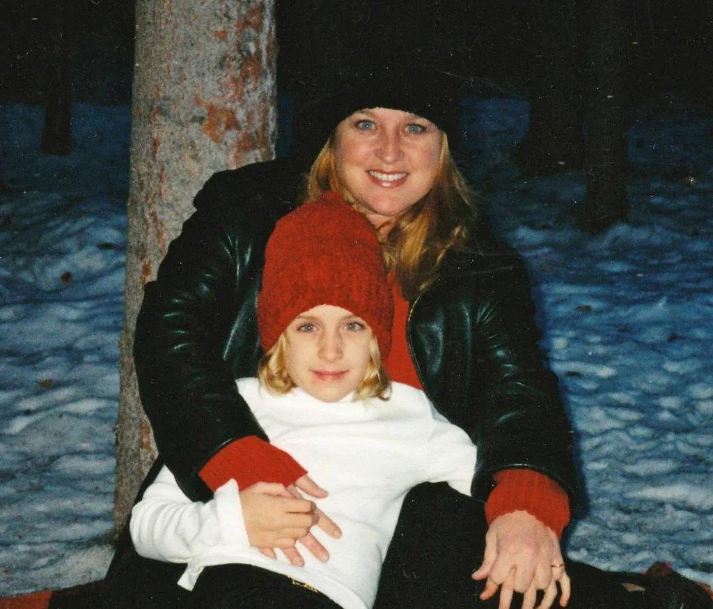 woman in black with girl in white with red hat