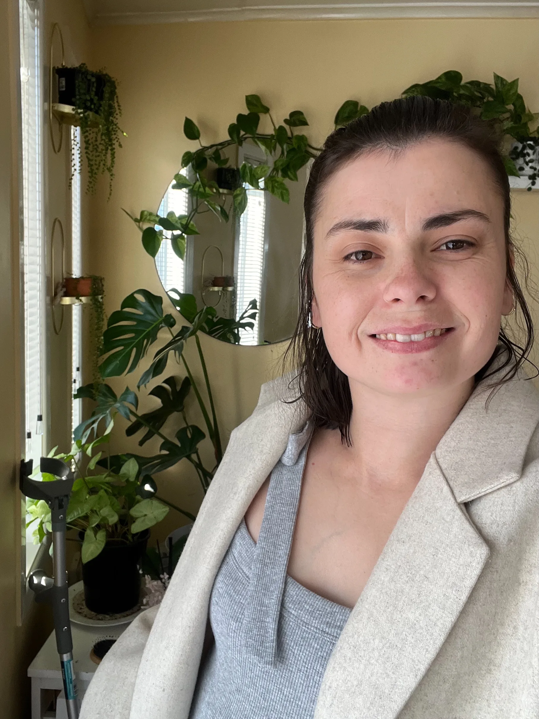  woman in grey shirt standing in front of plants she is inside