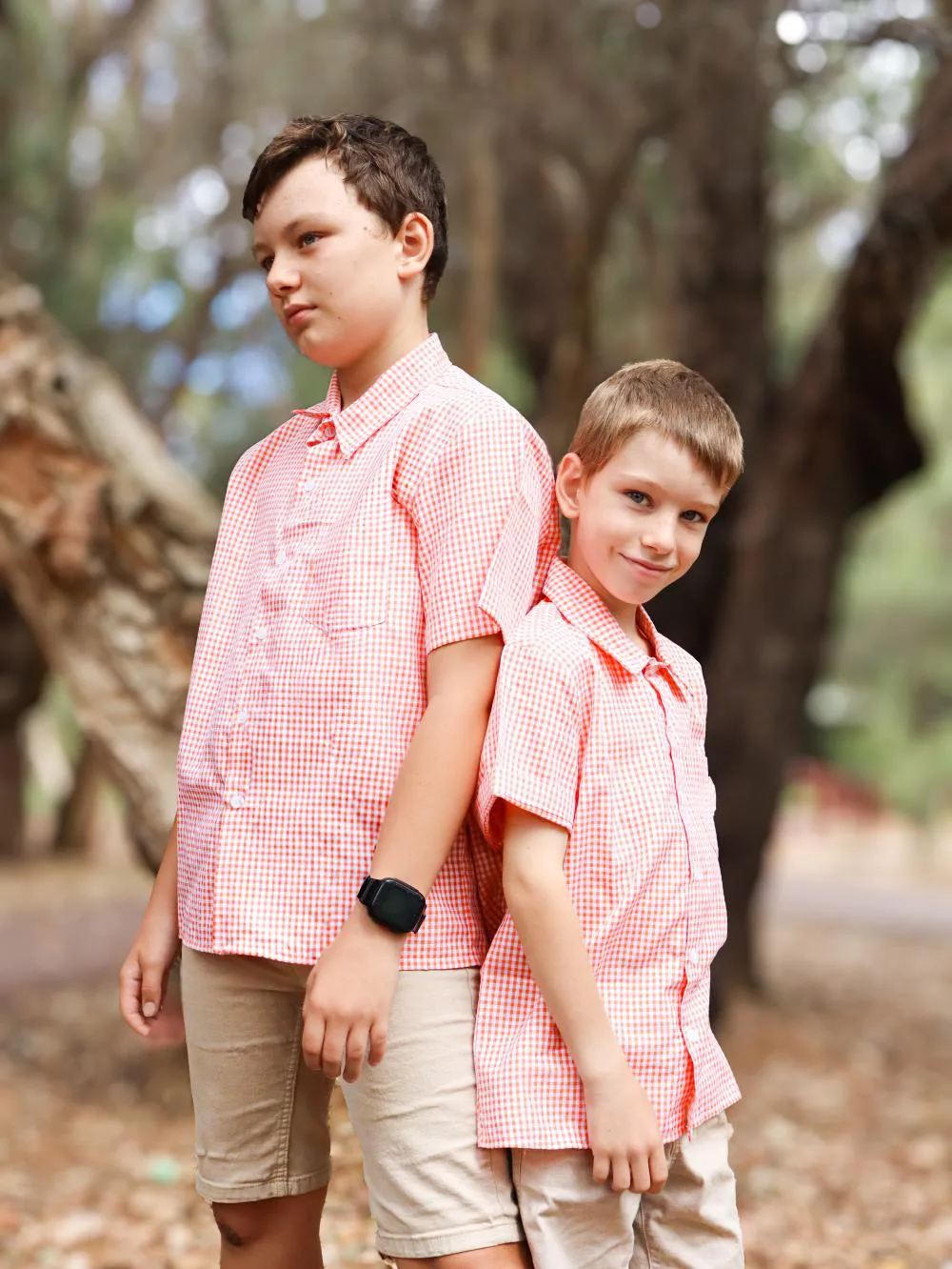 two boys, one taller and one shorter waring orange gingham shirts