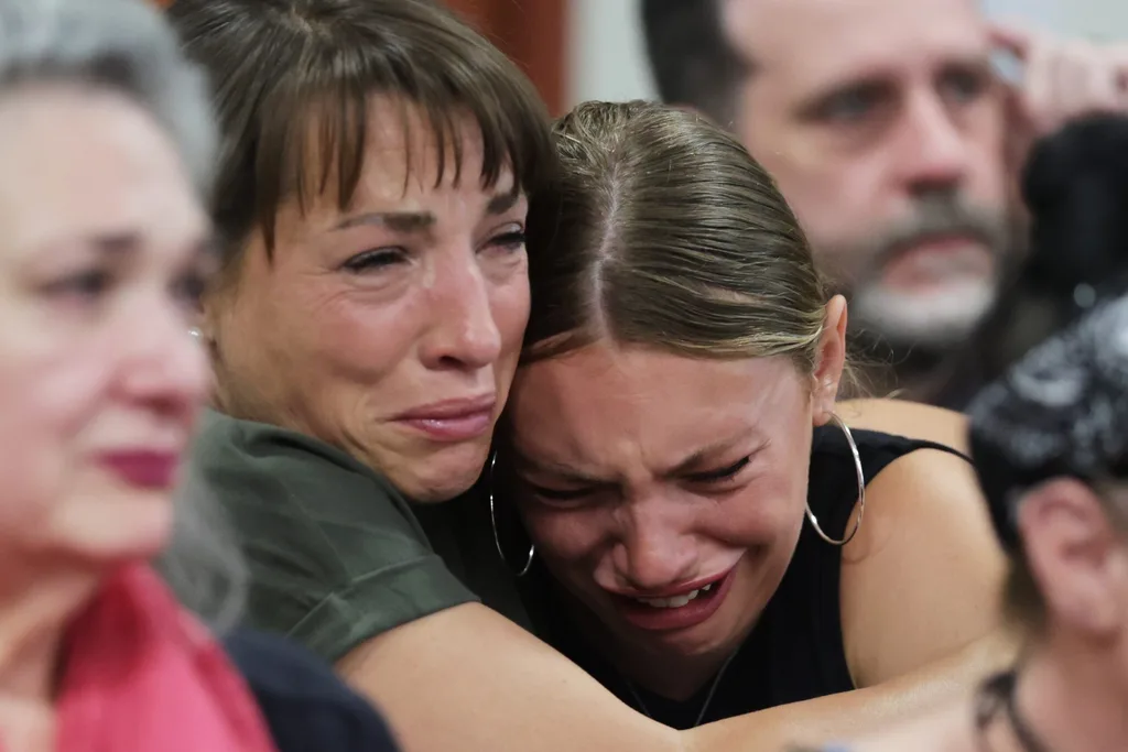 women clutching one another in court room sobbing