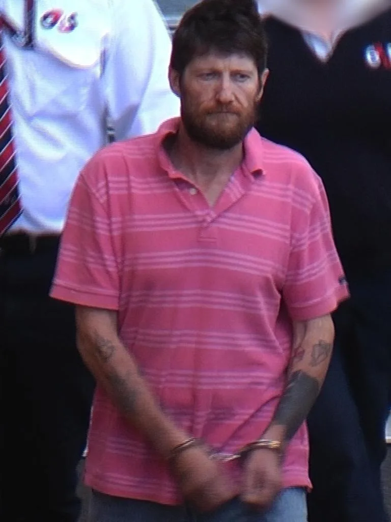 man in pink shirt with ttattos he is handcuffed