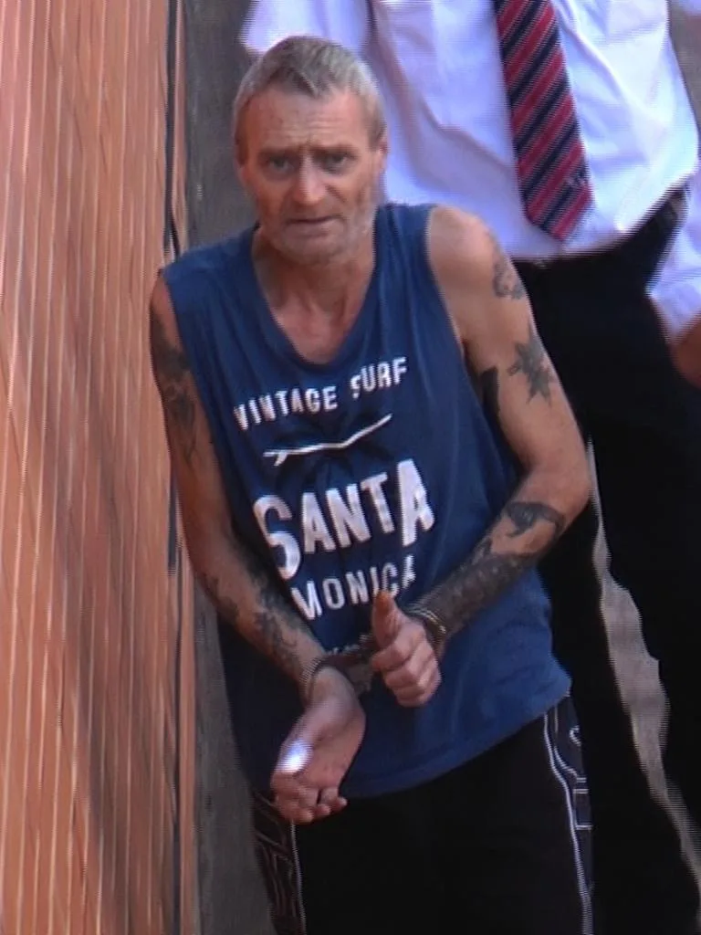 man in navy shirt that reads vintage surf santa monica he is handcuffed