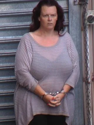 woman in grey striped shirt, hands in handcuffs in front of her