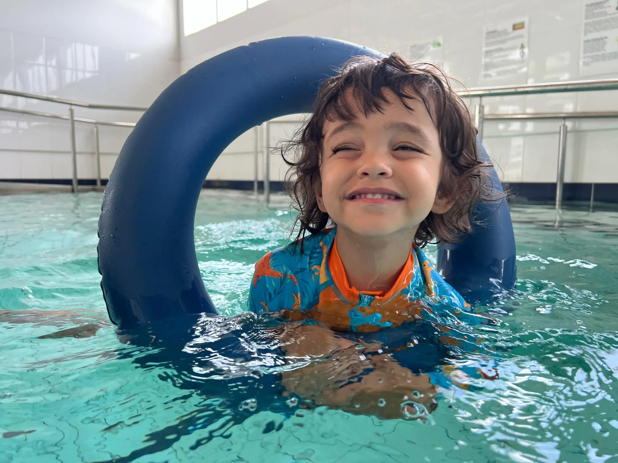 child swimming in a pool wearing a life ring
