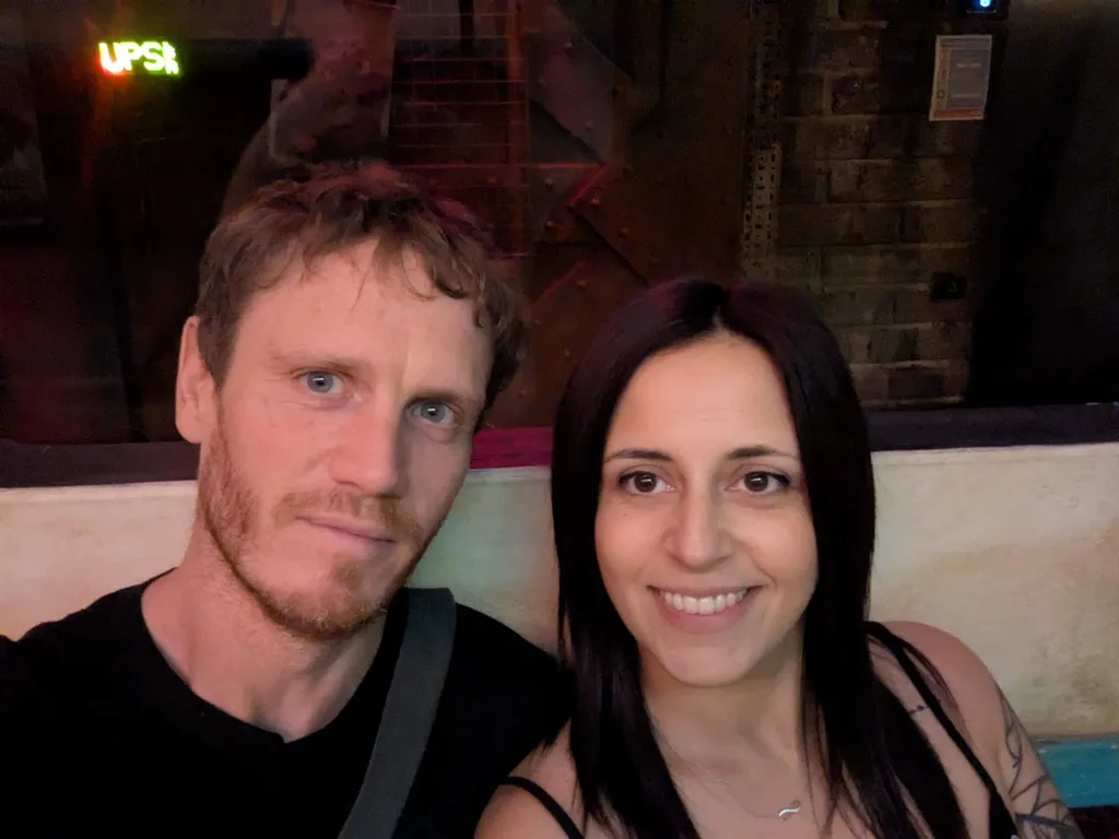 Woman with dark hair and man with facial hair in black tshirt smiling .