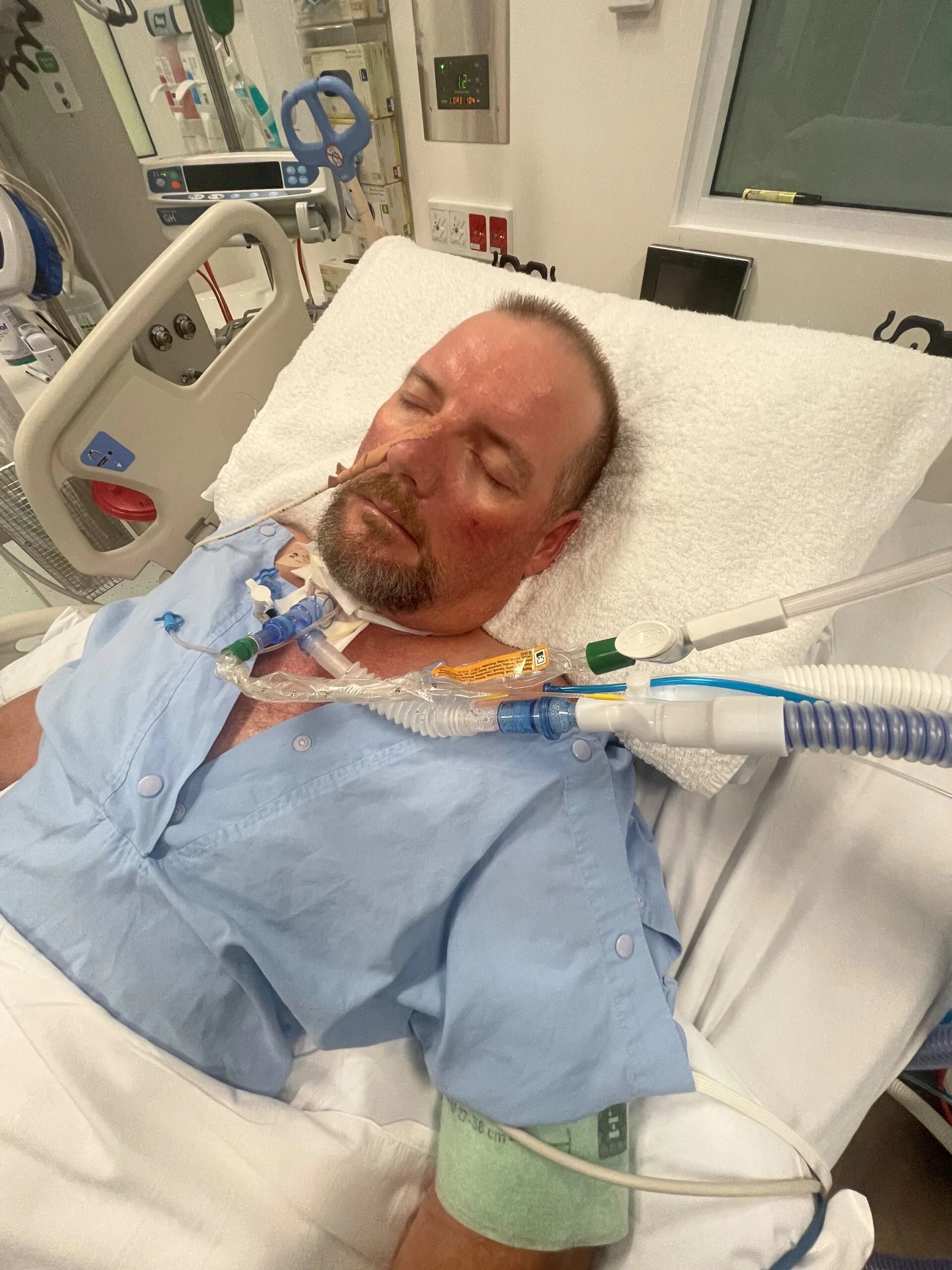 man at hospital in blue scrubs with wires and cords