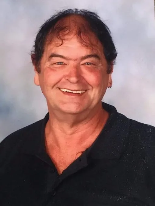 a man in black tshirt smiling for the camera