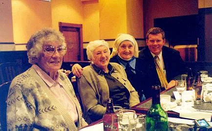 three women and a man in a suit sat at a table
