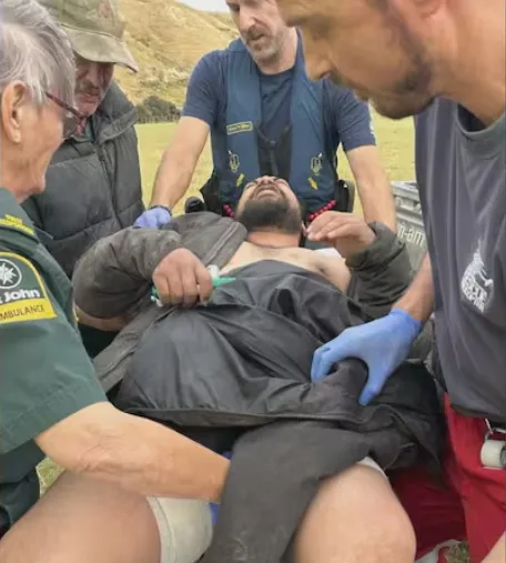 Eli on a stretcher with emergency responders surrounding him.