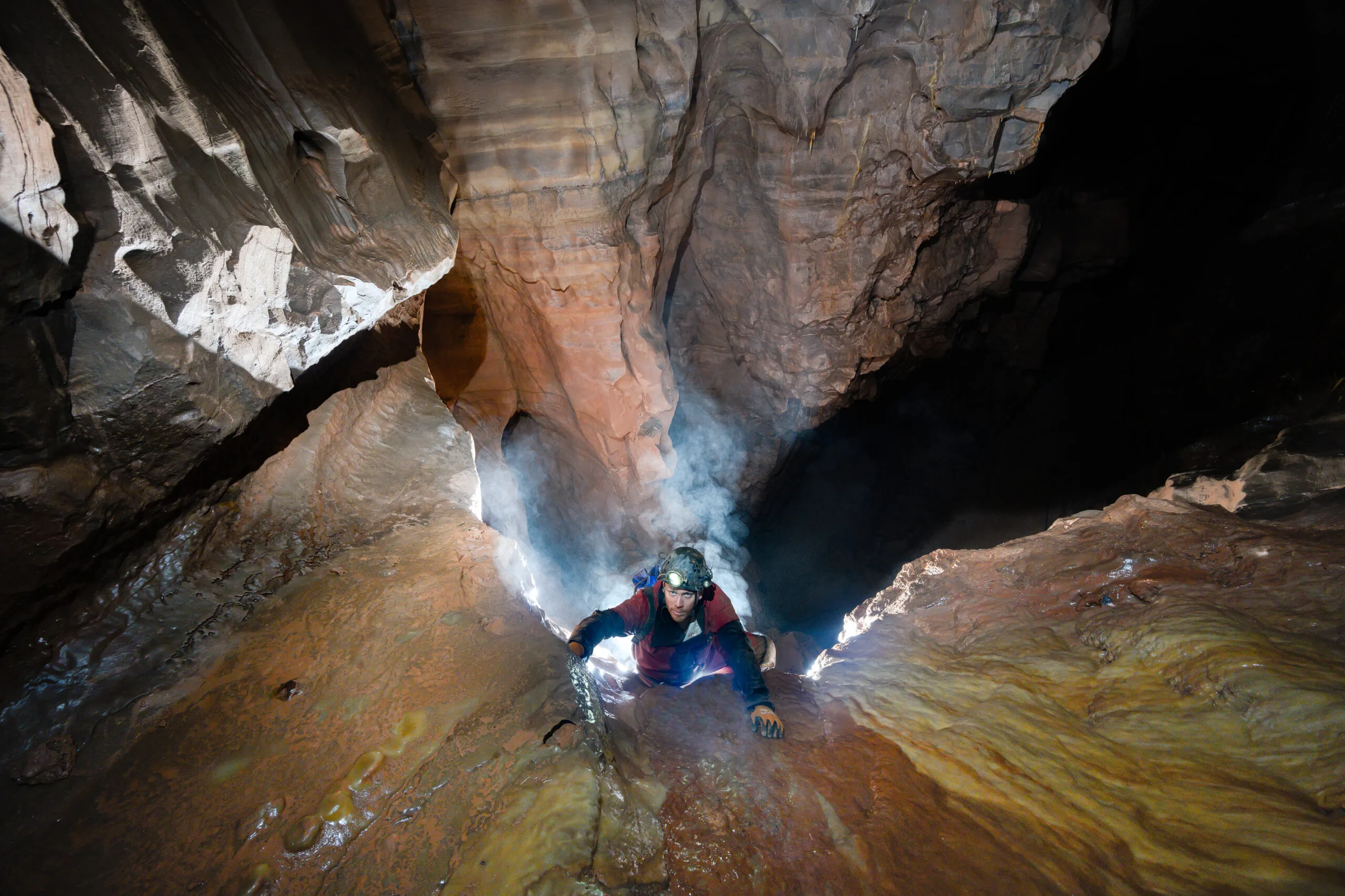 Man with headtorch on head caving with light behind hm