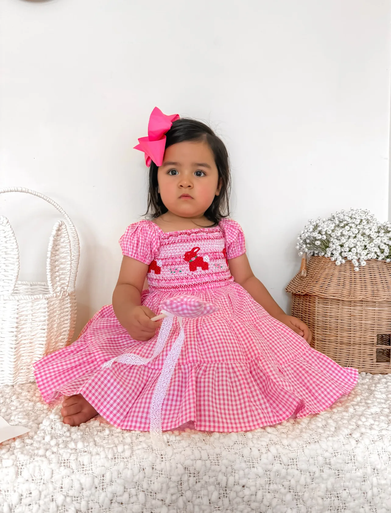 a young girl wearing a pink ginham dress, she had a pink bow in her hair