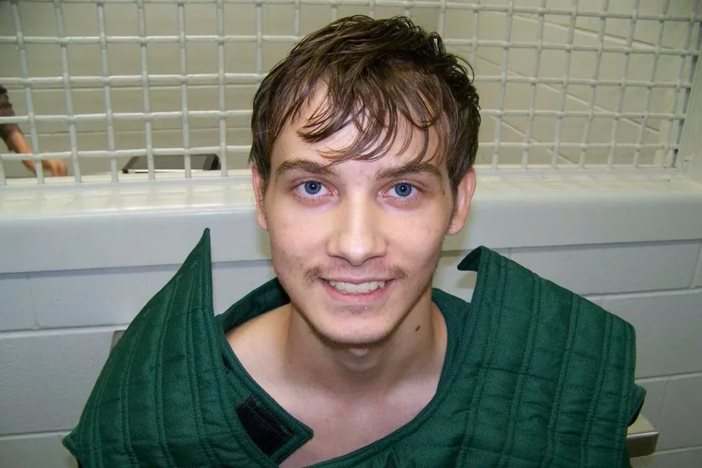 man in jail cell in green outfit