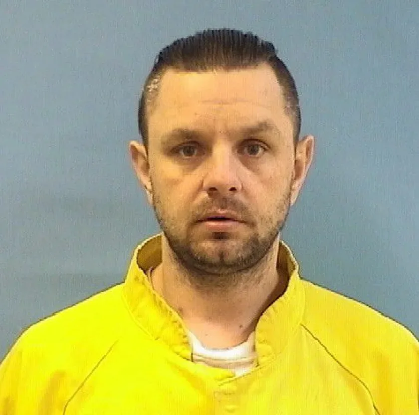 man with slick back hair in a yellow jumpsuit