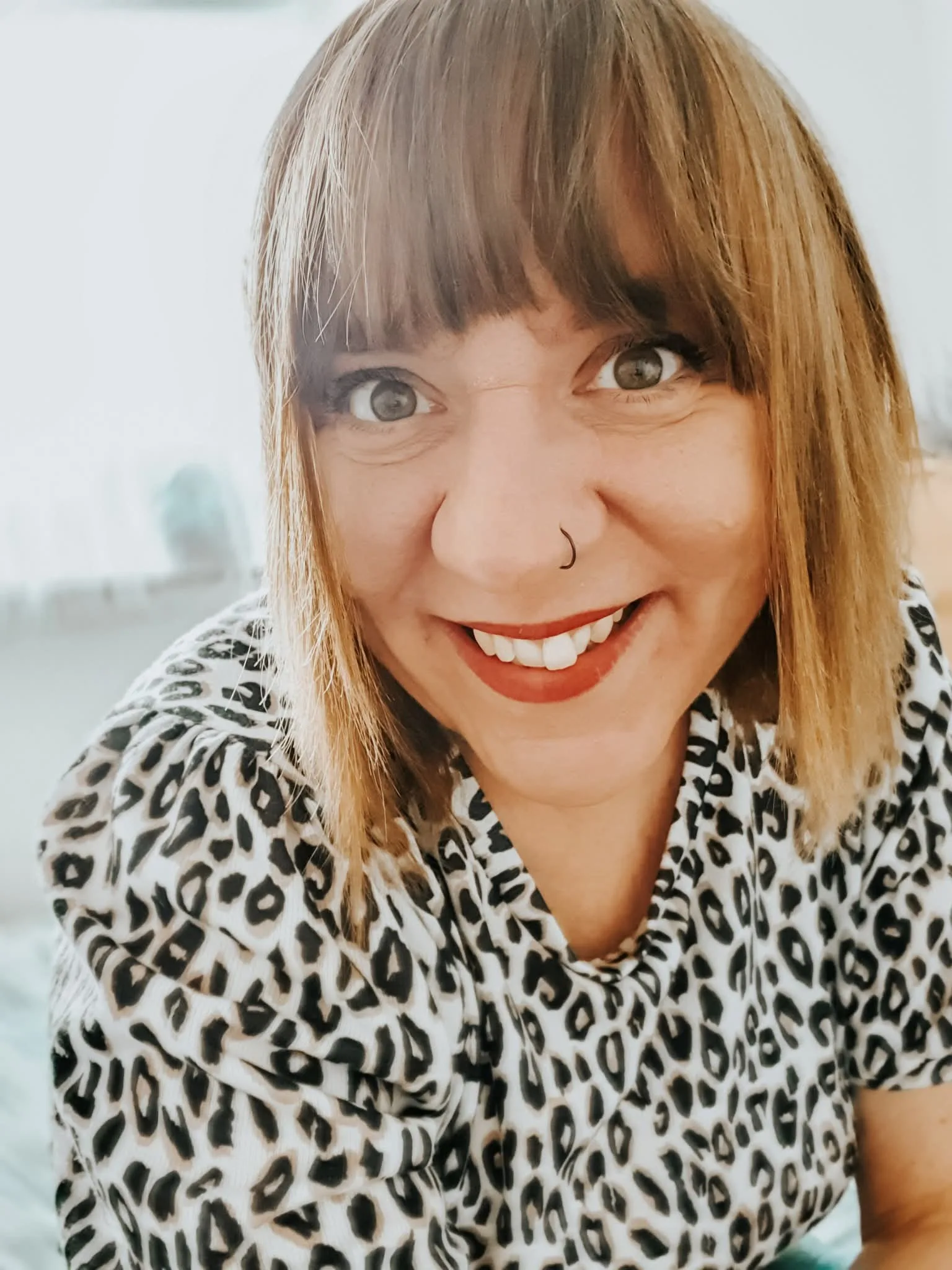 woman smiling at camera, waring printed shirt
