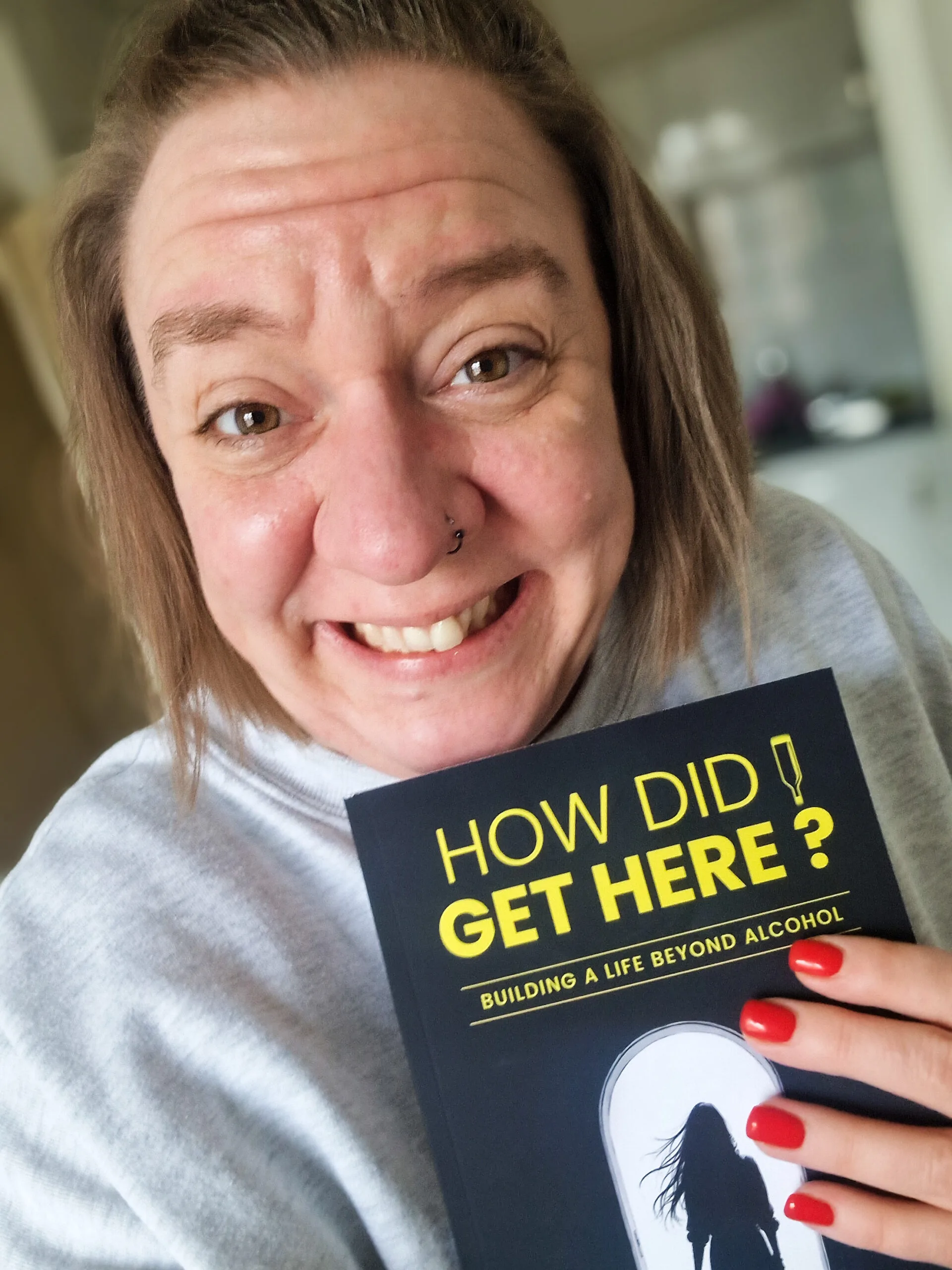 Woman smiling holding up a black book with yellow font.