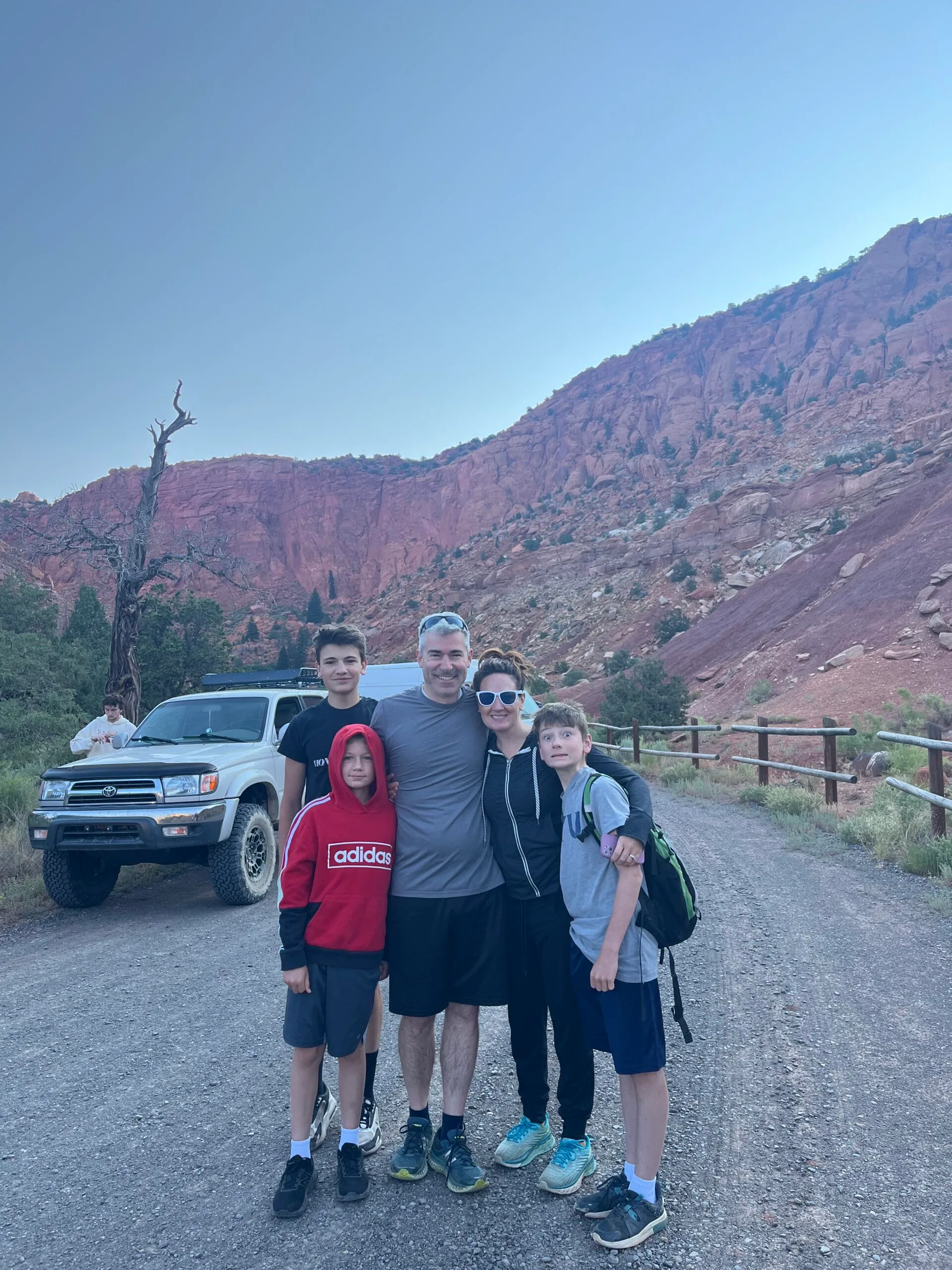 family photo of mother, son, and three sons in activewear outside with mountains in the background 