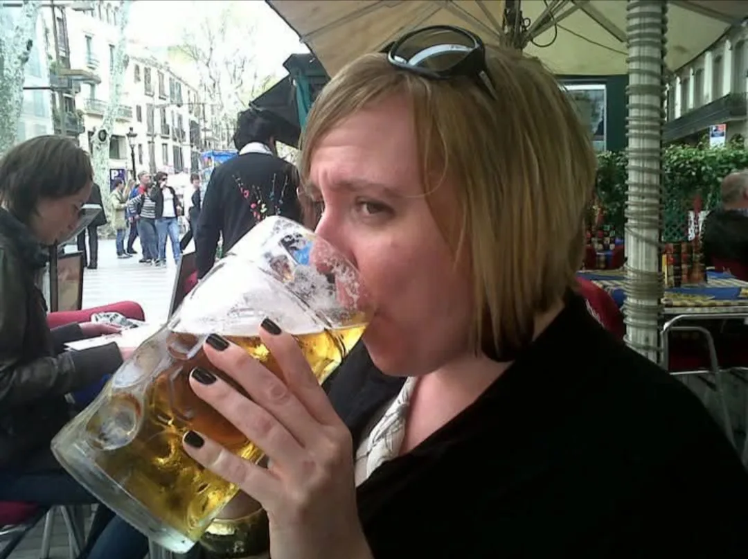 Woman drinking beer in black shirt.
