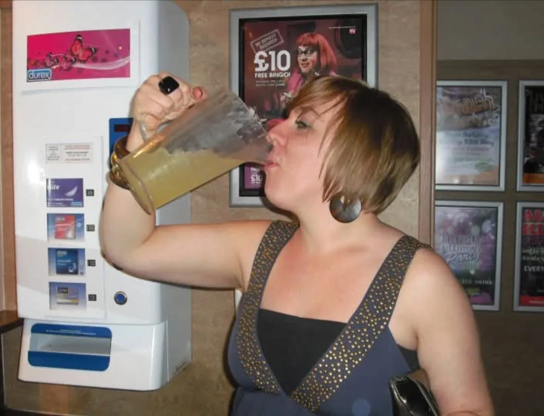 Woman with short hair wearing party outfit drinking beer.