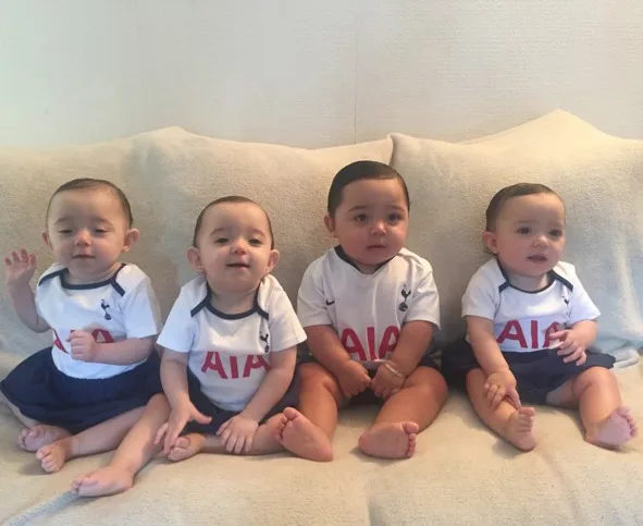 four babies in white jumpers sitting on the couch