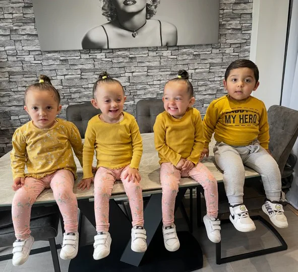 three girls in pink leggings and yellow shirts, and one boy in yellow jumper and grey sweat pants