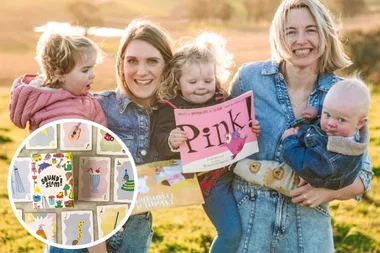 Two women each carrying a children in their arms outside in a field