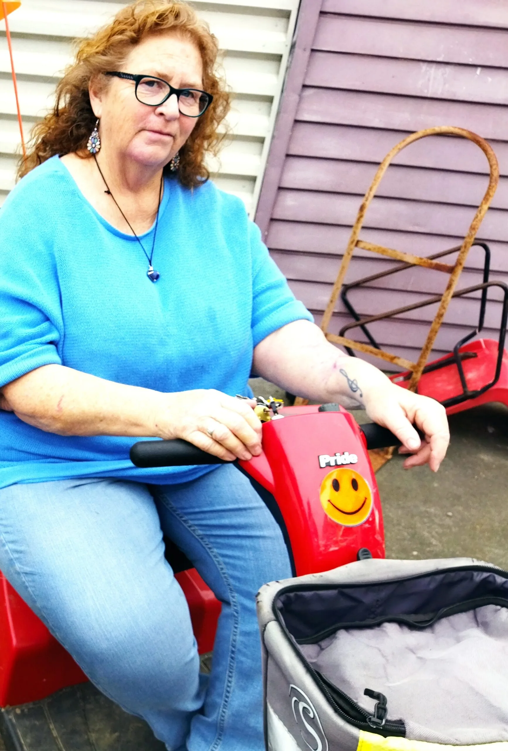 Woman in blue shirt and jeans on a mobility scooter.