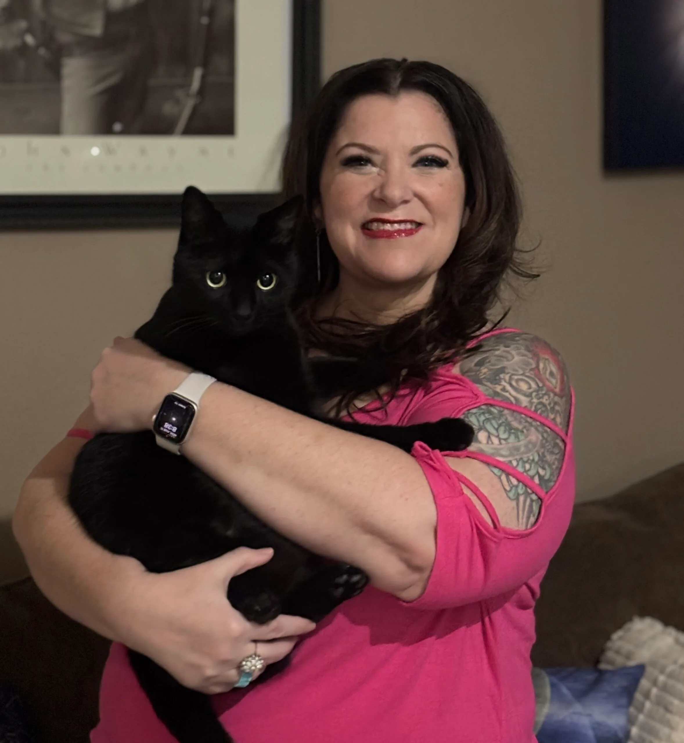Woman in pink top holds black cat
