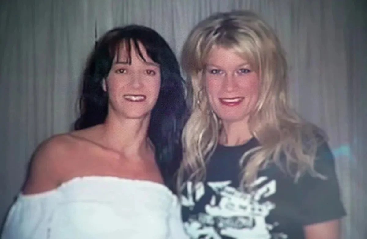 a brunette woman in a white blouse and blonder woman in black tshirt 