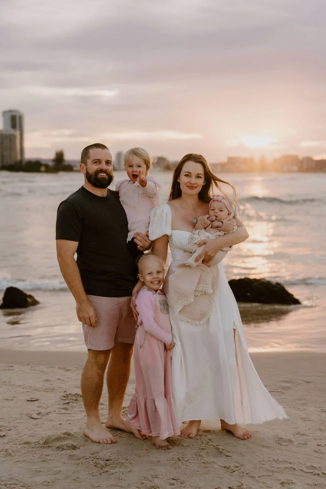 a family of four taking photos at the beach