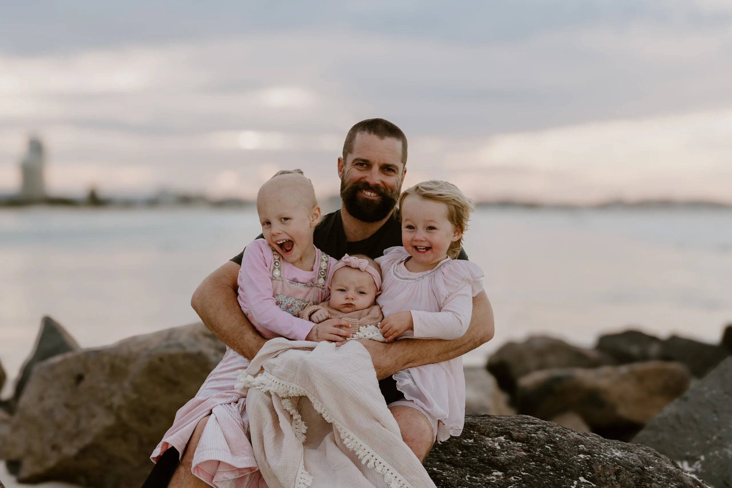 three girls in pink, hubby in black tee at beach