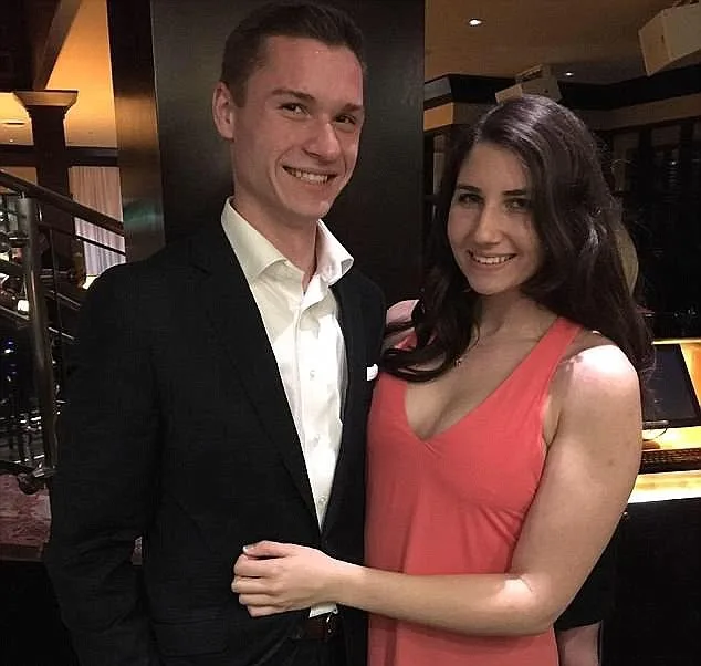 Man on the left wearing black suit and woman on the right in peach coloured dress smiling at camera.