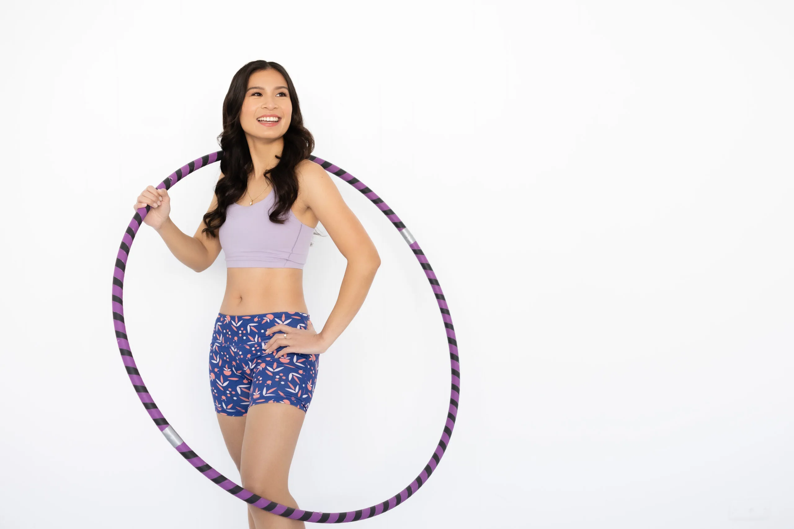 Image of woman wearing active wear singlet and shorts and holding hula hoop