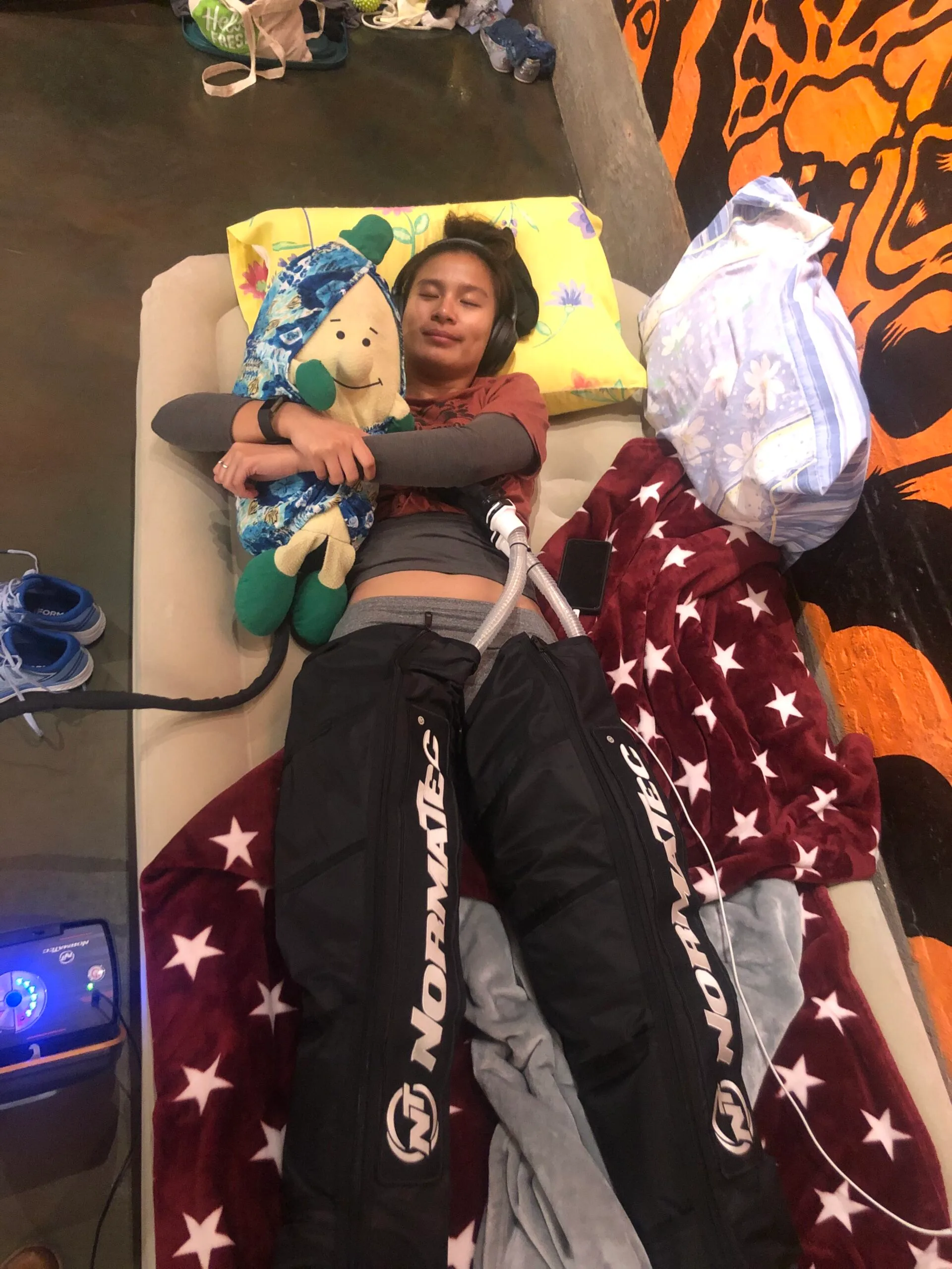 Image of hula hoop champion laying on inflatable mattress and wearing compression boots.