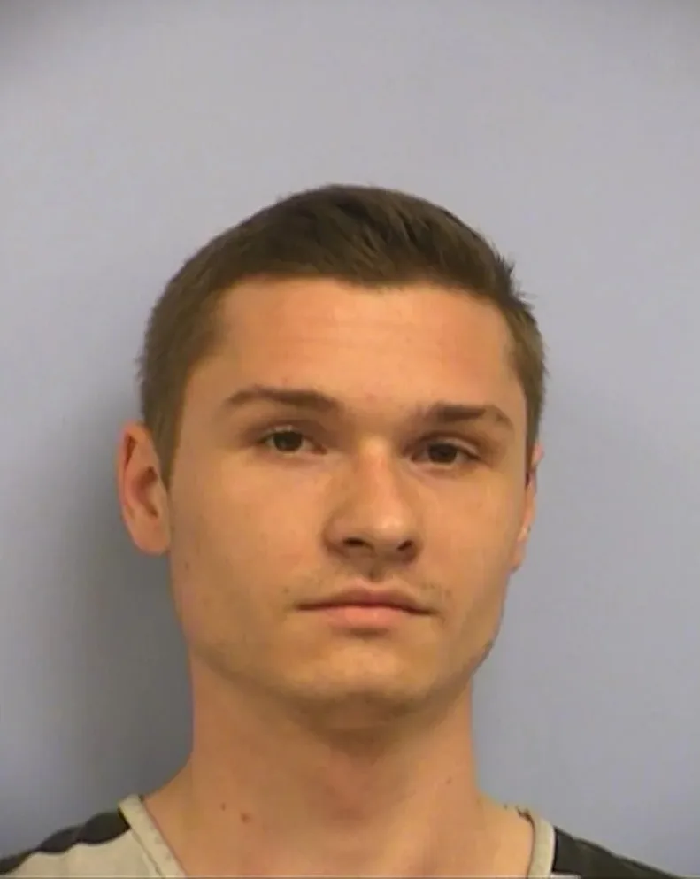 Man with short hair in prison uniform staring at camera.