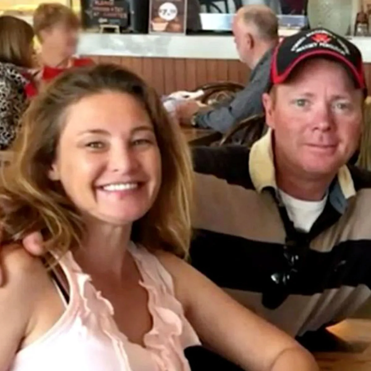 woman with dark hair smiling smiling and man in striped top and hat