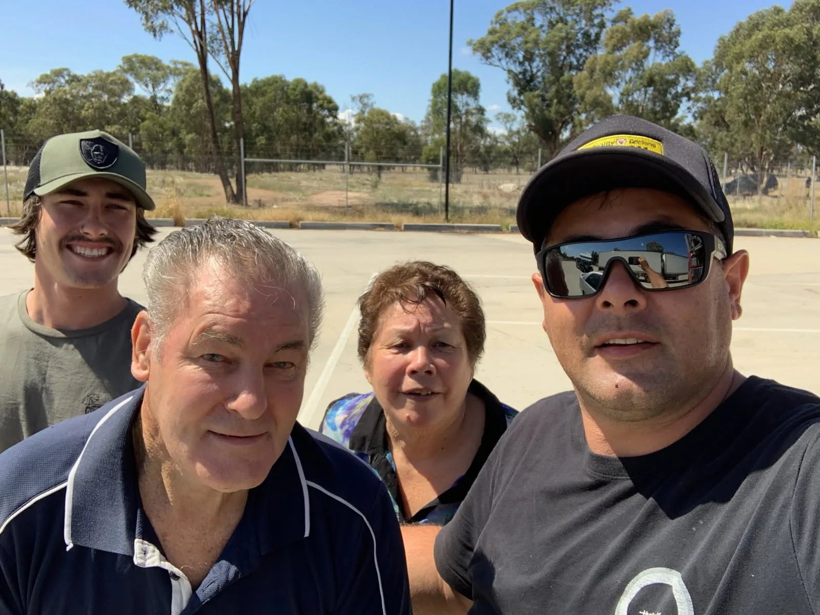 Three men in in black tshirts and one woman standing 
