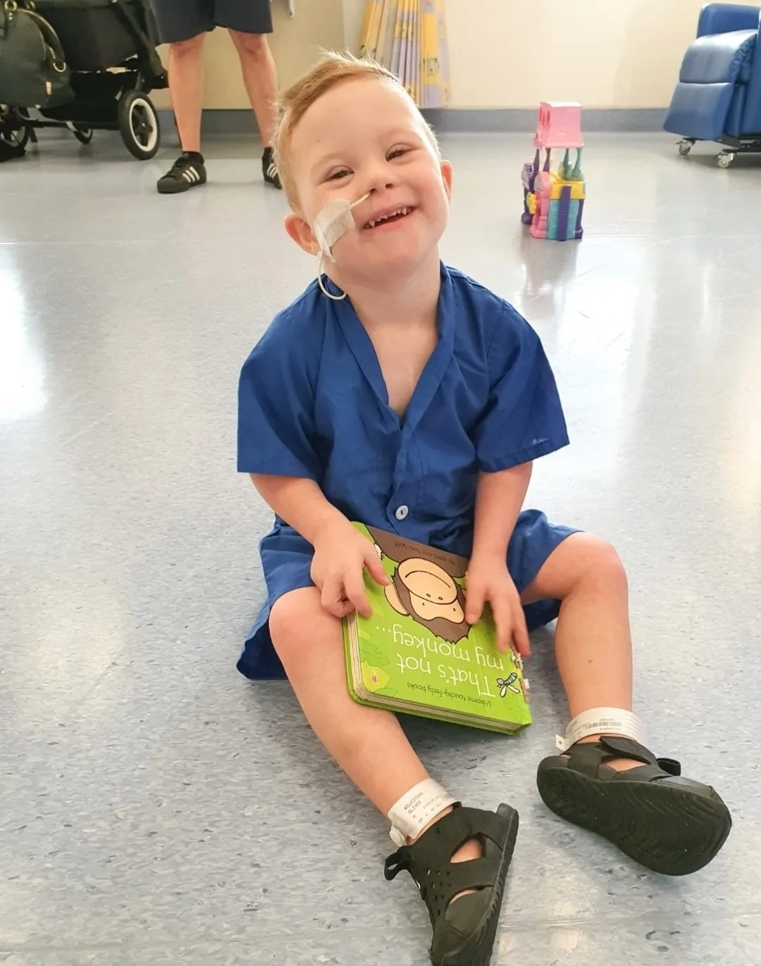 kid in hospital with a feeding tube, reading a green book